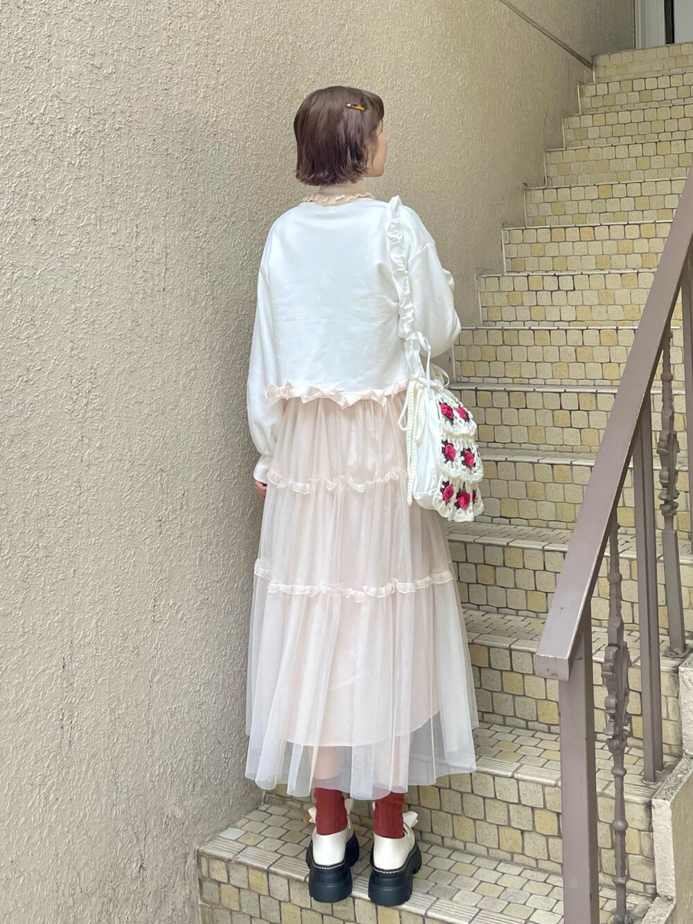 ホワイト系のニット/セーター、ピンク系のワンピース、ホワイト系のショルダーバッグを着用したレディースの冬コーディネートの2枚目の写真