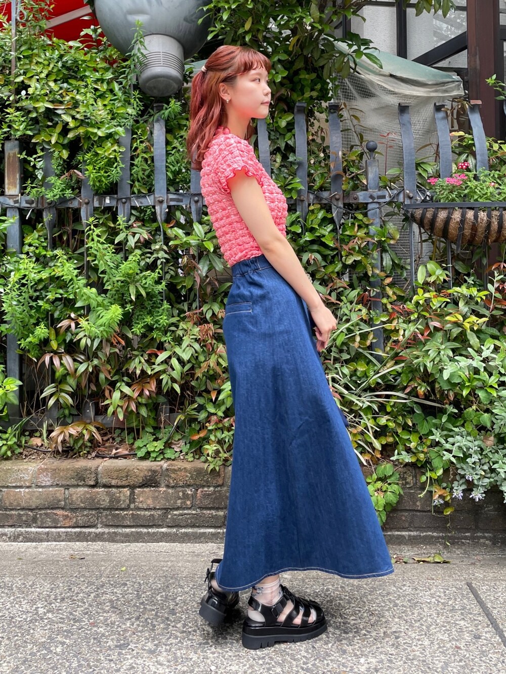 ブルー系のデニムスカート、レッド系のTシャツ/カットソー、ブラック系のサンダルを着用したレディースの春コーディネートの2枚目の写真