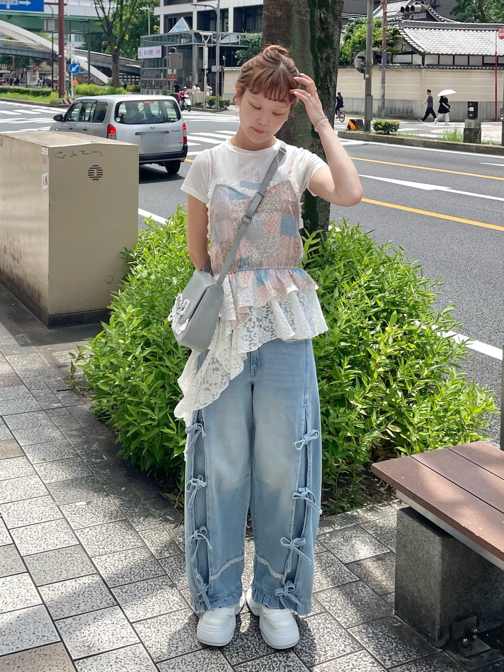 ブルー系のデニムパンツ、ブルー系のショルダーバッグ、ホワイト系のスニーカーを着用したレディースの夏コーディネートの2枚目の写真