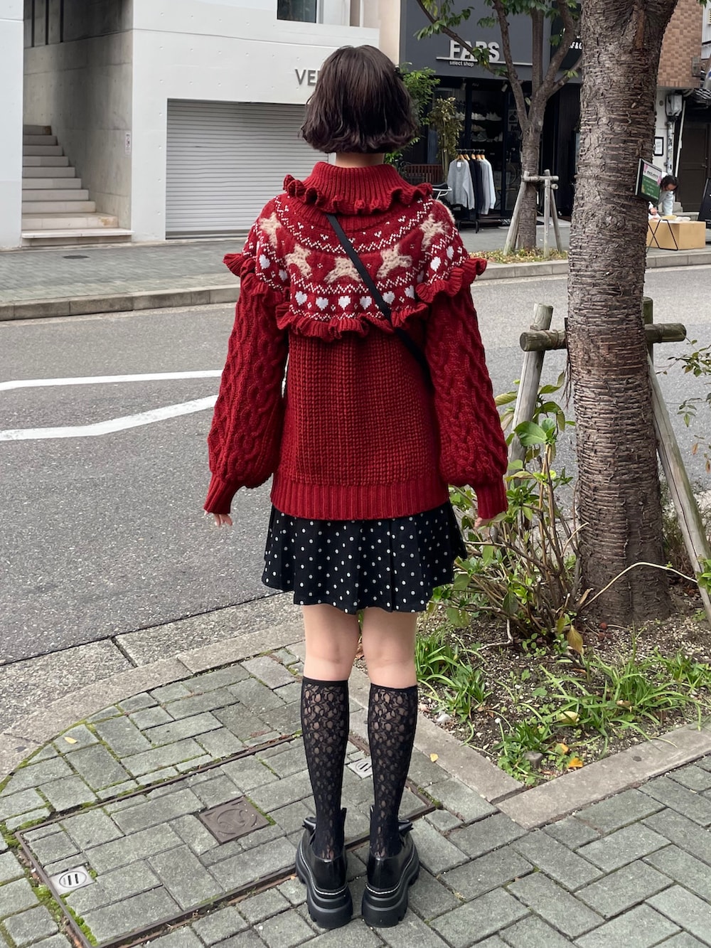 ブラック系のローファー、レッド系のニット/セーター、ブラック系のスカートを着用したレディースの秋コーディネートの2枚目の写真