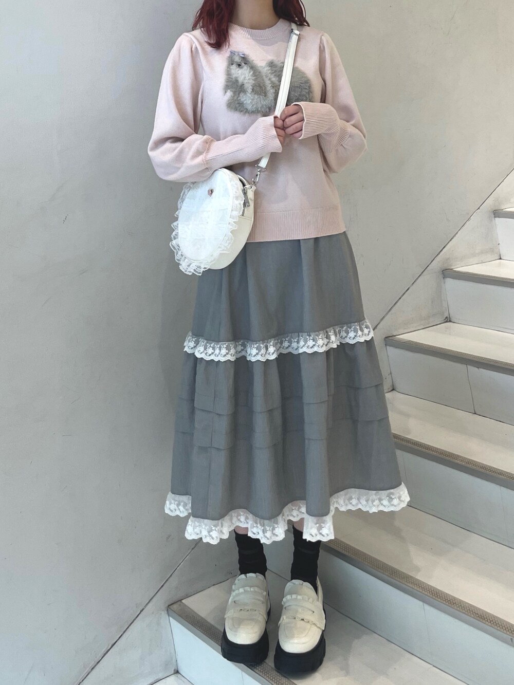 ピンク系のニット/セーター、グレー系のスカート、ホワイト系のショルダーバッグを着用したレディースの秋コーディネートの2枚目の写真