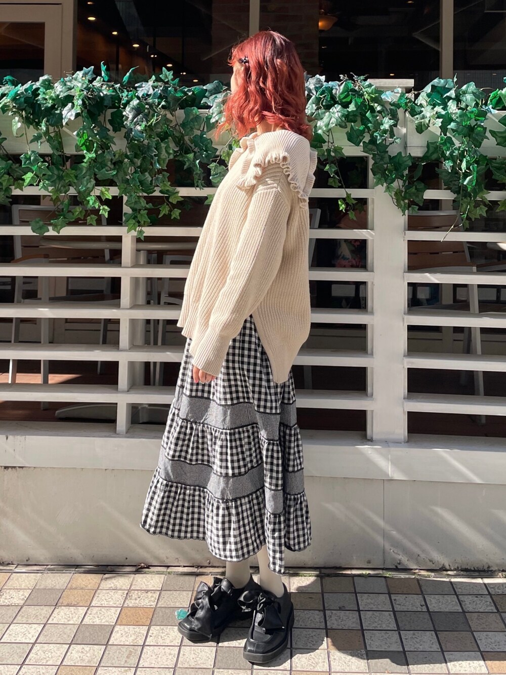 ホワイト系のニット/セーター、ブラック系のスカート、ブラック系のモカシン/デッキシューズを着用したレディースの冬コーディネートの2枚目の写真