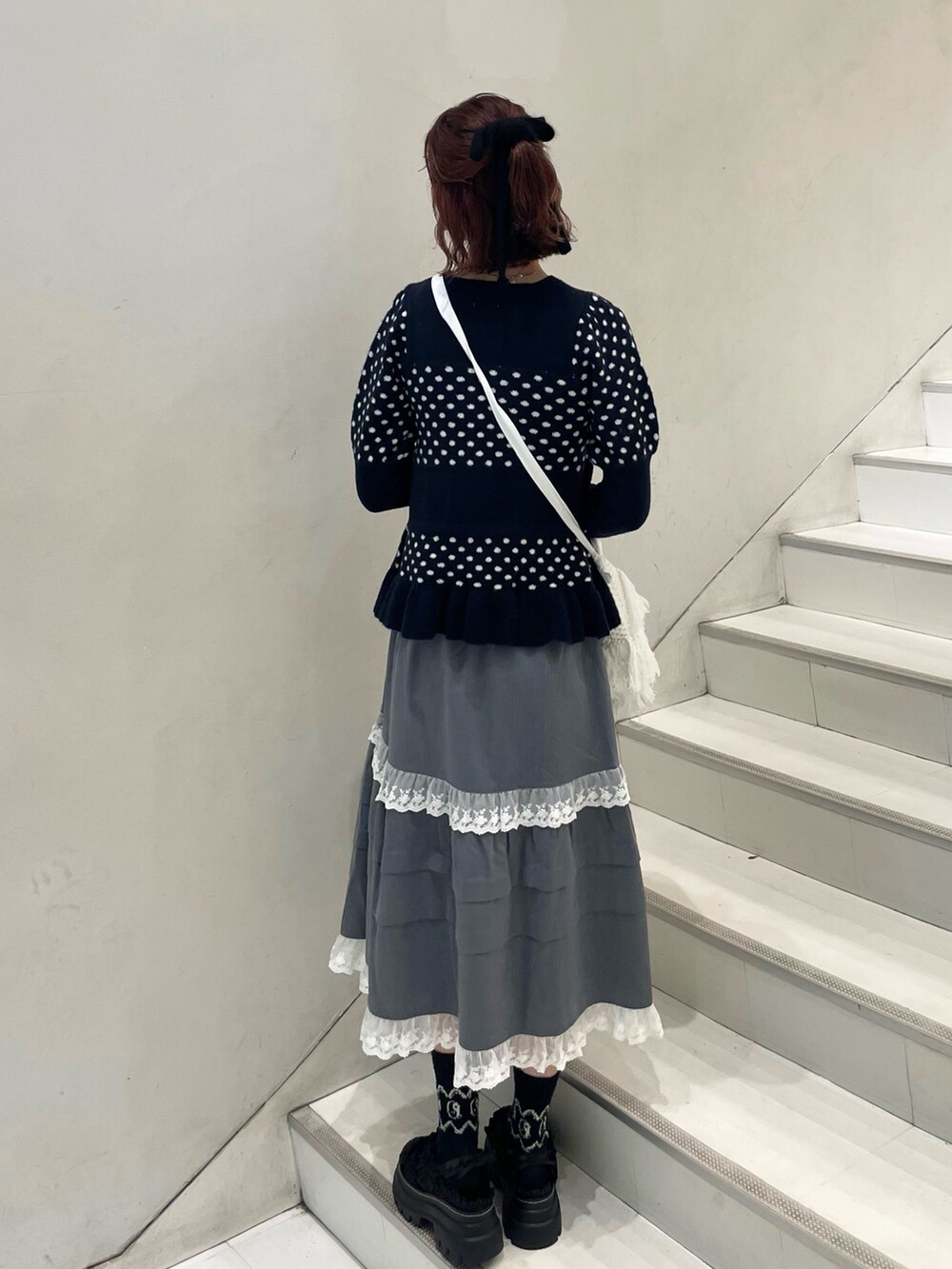 ブルー系のニット/セーター、グレー系のスカート、ホワイト系のショルダーバッグを着用したレディースの秋コーディネートの4枚目の写真