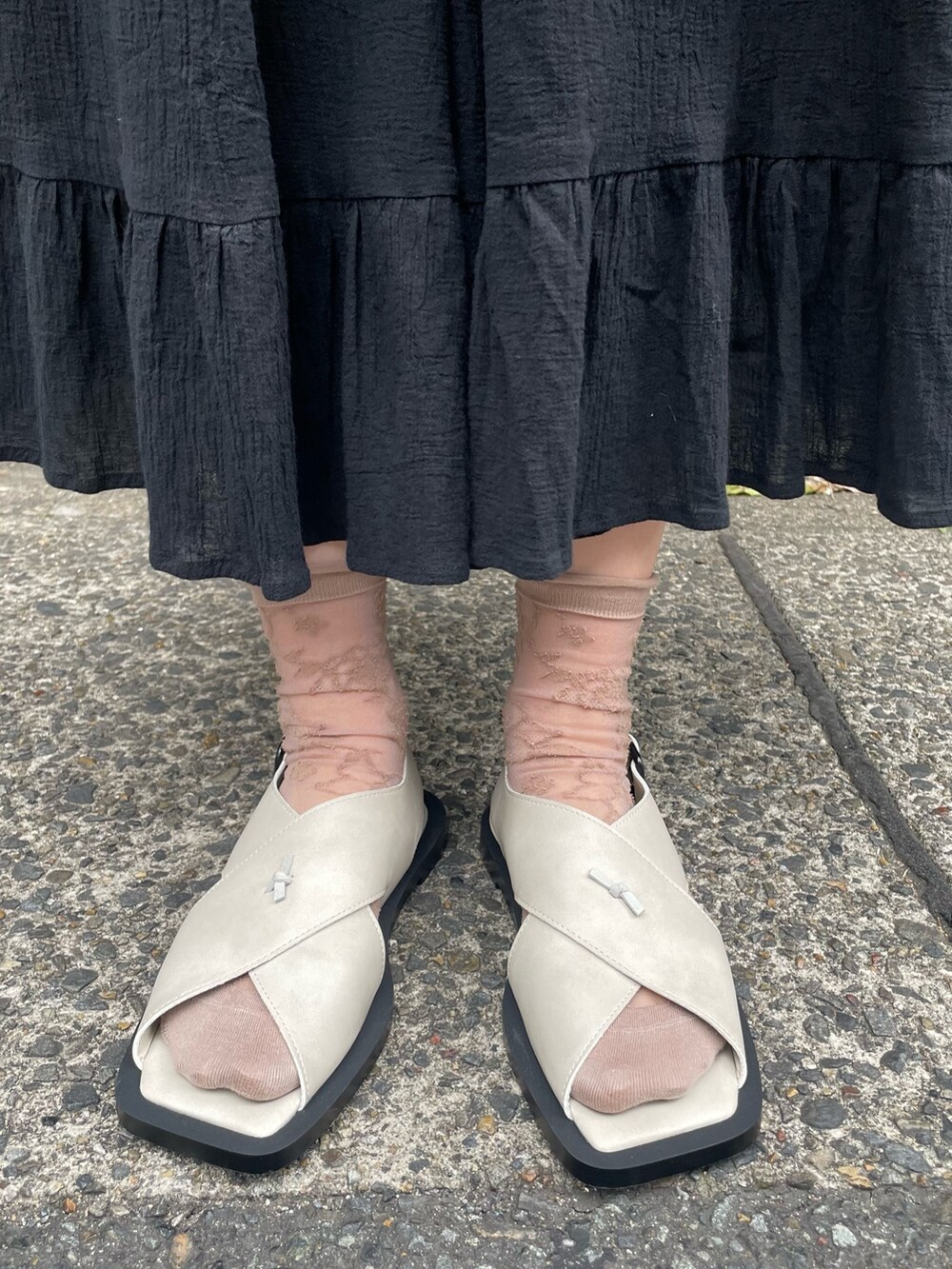 ブラック系のスカート、ホワイト系のTシャツ/カットソー、グレー系のサンダルを着用したレディースの春コーディネートの6枚目の写真