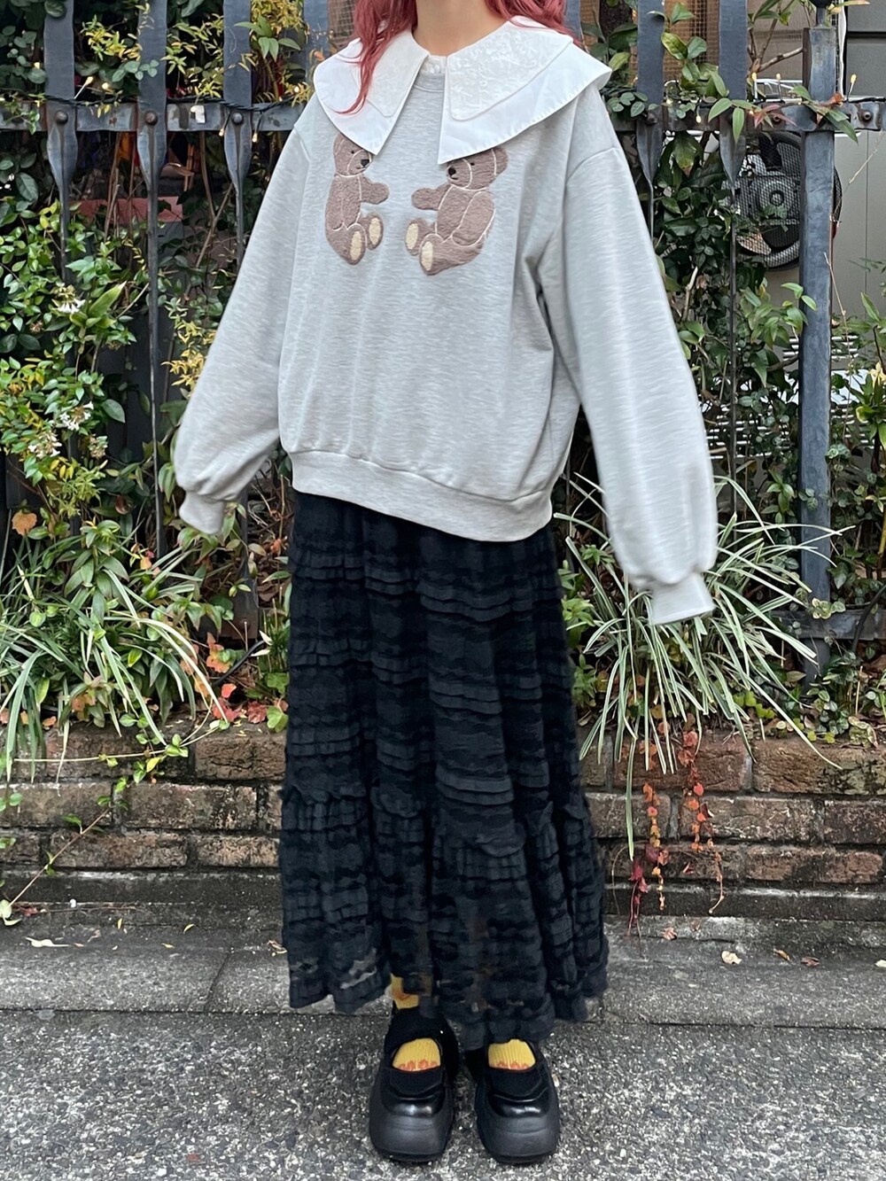 グレー系のスウェット、ブラック系のスカート、ブラック系のスニーカーを着用したレディースの冬コーディネートの2枚目の写真