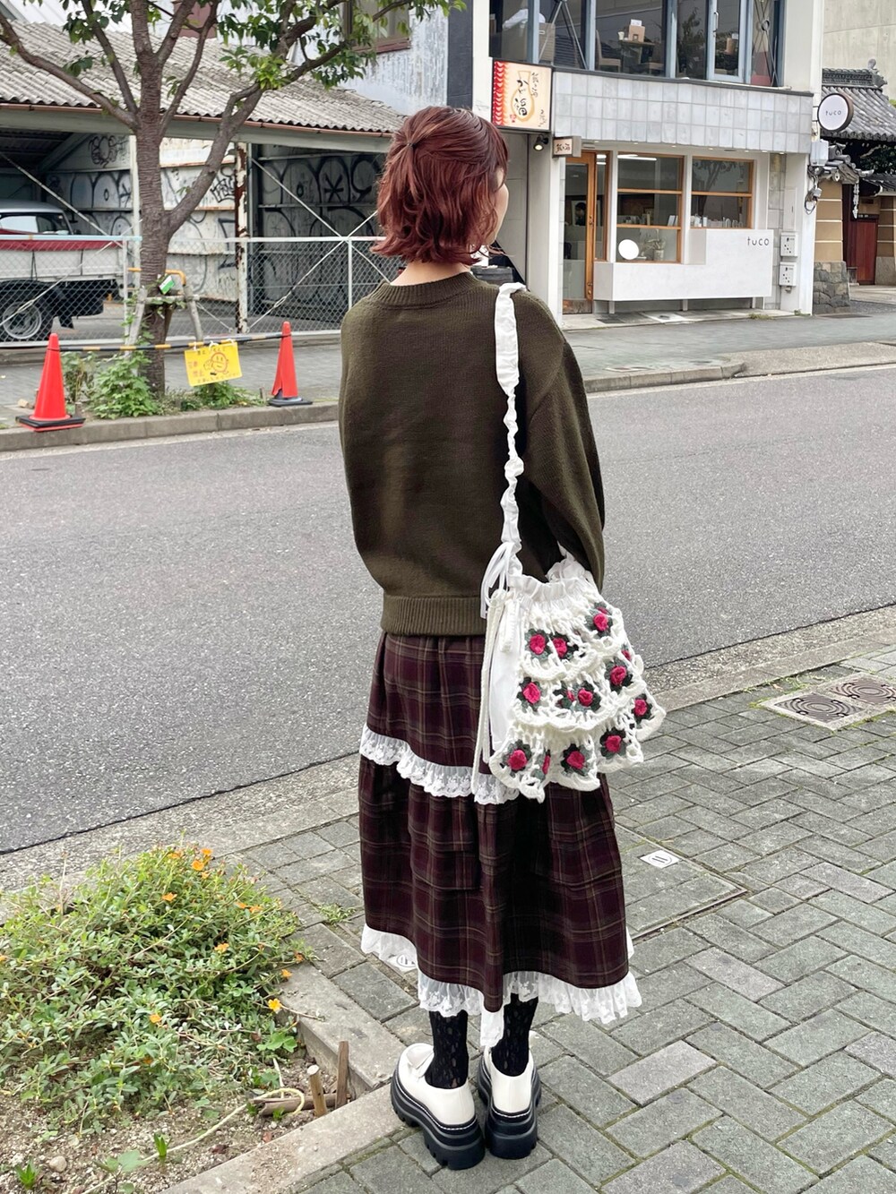 グリーン系のニット/セーター、ホワイト系のショルダーバッグ、ブラウン系のスカートを着用したレディースの秋コーディネートの7枚目の写真