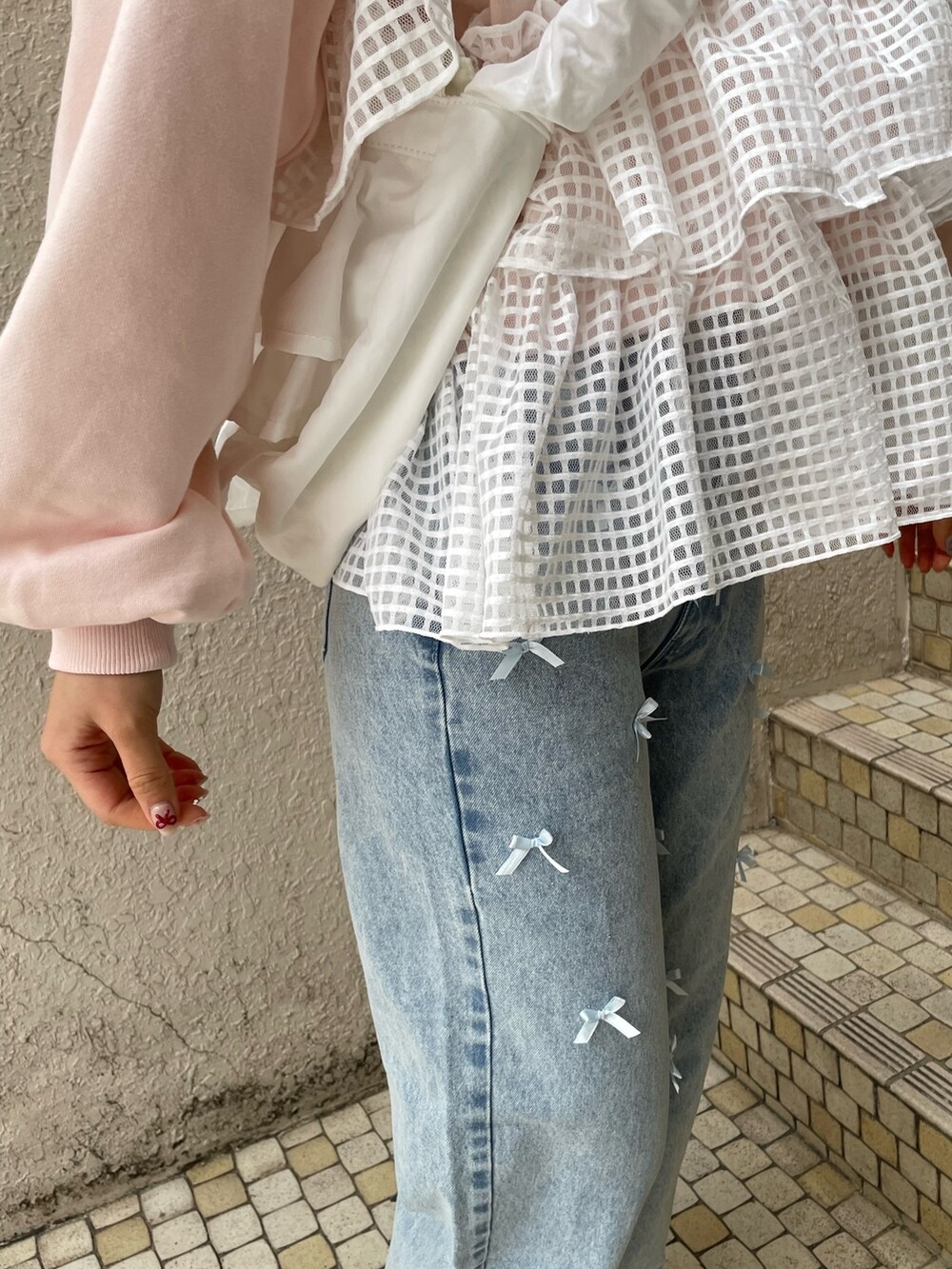 ブルー系のデニムパンツ、ピンク系のスウェット、ホワイト系のショルダーバッグを着用したレディースの冬コーディネートの7枚目の写真