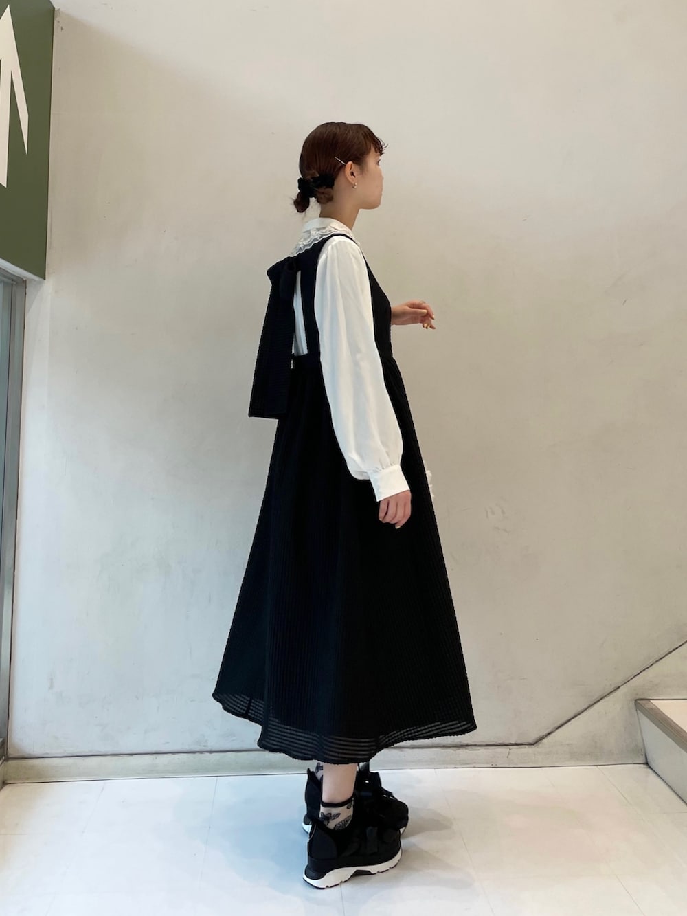 ブラック系のワンピース、ホワイト系のトートバッグ、ブラック系のスニーカーを着用したレディースの春コーディネートの2枚目の写真