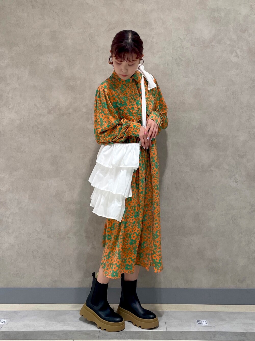 ブラック系のブーツ、グリーン系のワンピース、ホワイト系のトートバッグを着用したレディースの冬コーディネートの2枚目の写真