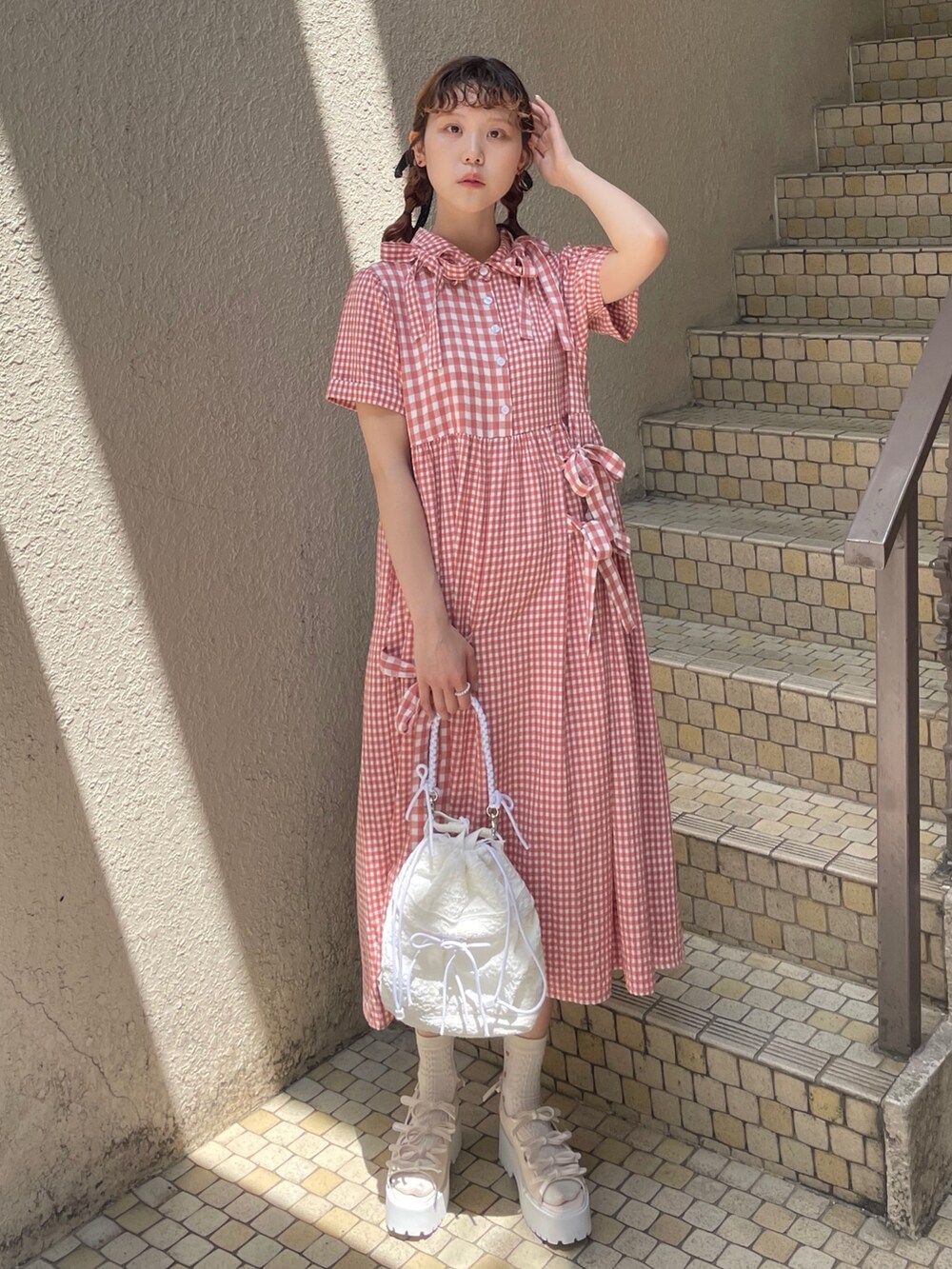 レッド系のワンピース、ホワイト系のショルダーバッグ、ホワイト系のサンダルを着用したレディースの春コーディネートの2枚目の写真