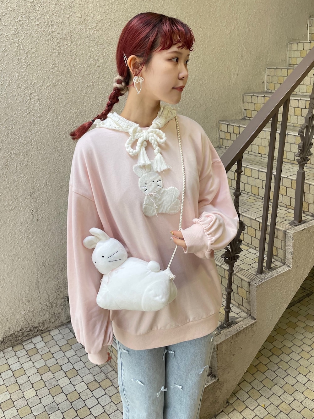 ブルー系のデニムパンツ、ピンク系のスニーカー、ホワイト系のショルダーバッグを着用したレディースの冬コーディネートの3枚目の写真