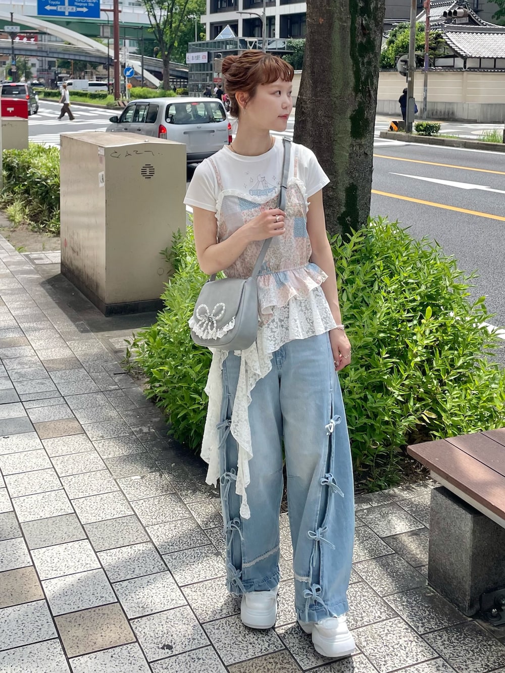 ブルー系のデニムパンツ、ブルー系のショルダーバッグ、ホワイト系のスニーカーを着用したレディースの夏コーディネートの4枚目の写真