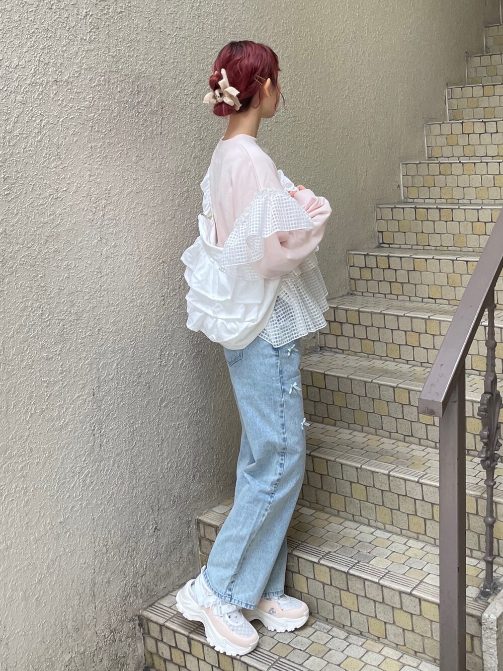 ブルー系のデニムパンツ、ピンク系のスウェット、ホワイト系のショルダーバッグを着用したレディースの冬コーディネートの3枚目の写真