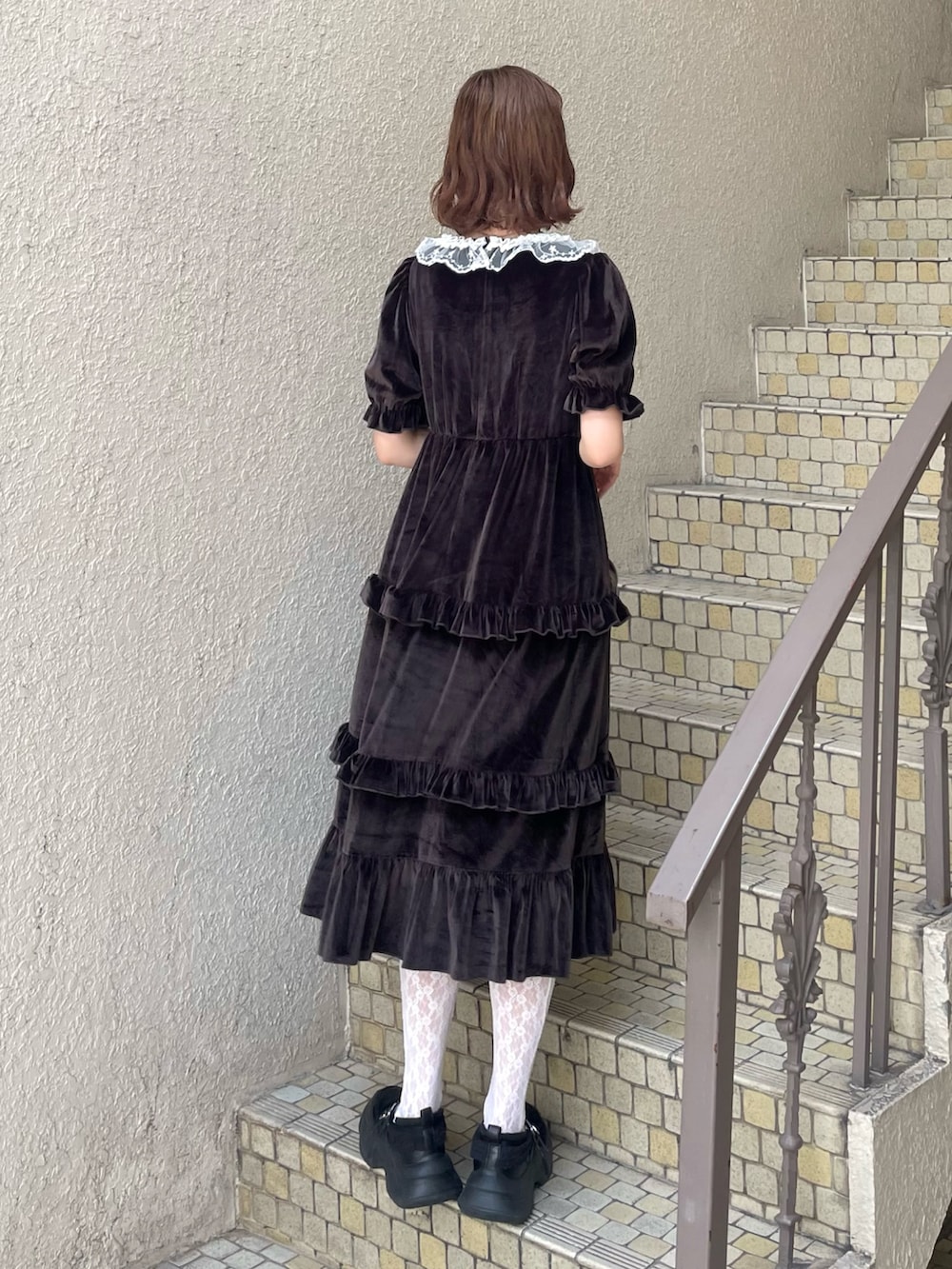 ブラウン系のハンドバッグ、ブラウン系のワンピース、ブラック系のスニーカーを着用したレディースの夏コーディネートの4枚目の写真
