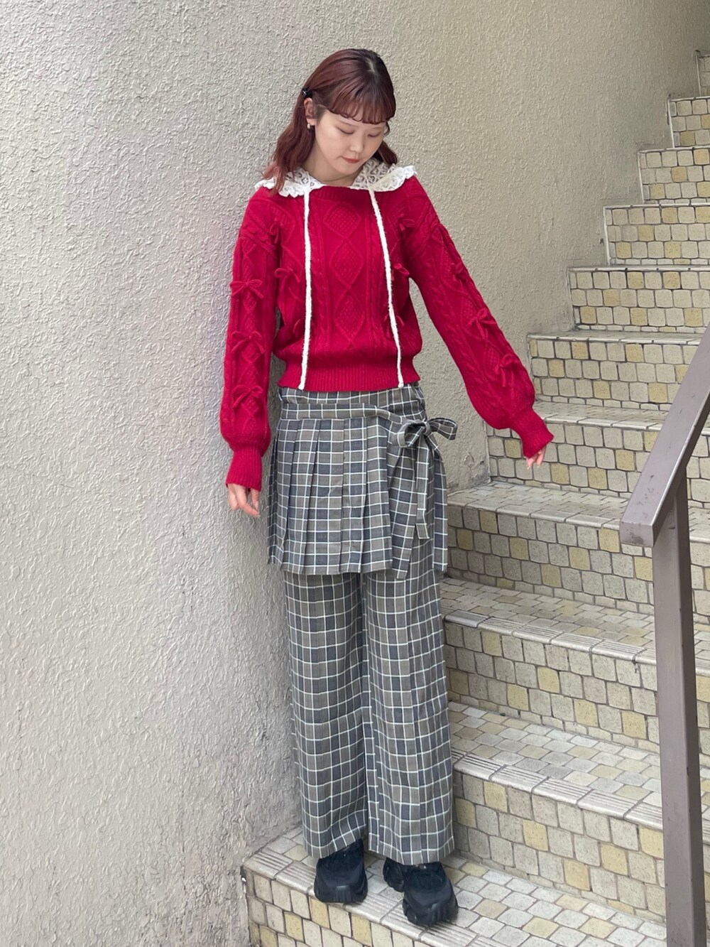 レッド系のニット/セーター、グリーン系のスラックス、ホワイト系のTシャツ/カットソーを着用したレディースの秋コーディネートの3枚目の写真