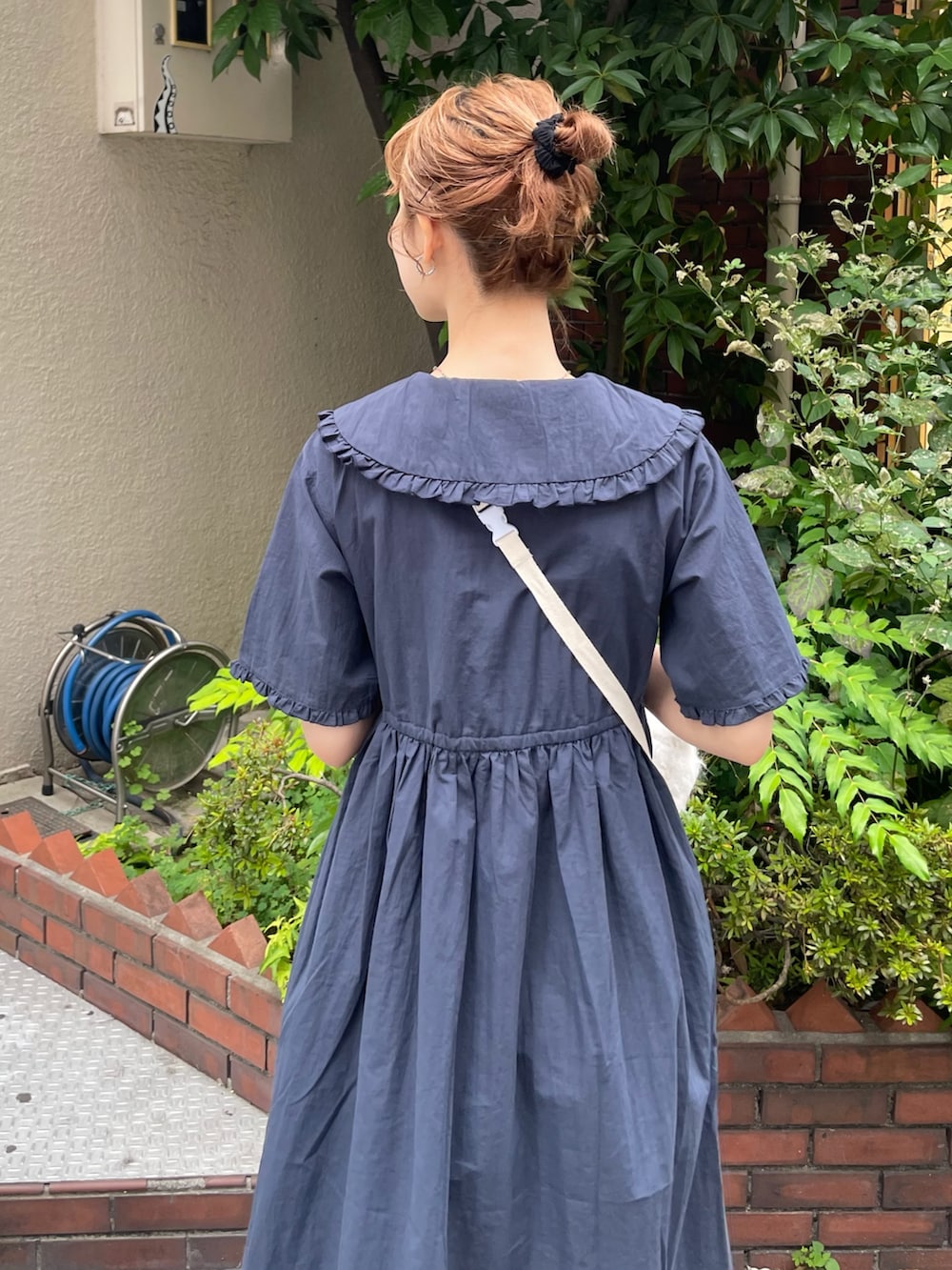 ブルー系のワンピース、ブラック系のスニーカー、ホワイト系のショルダーバッグを着用したレディースの夏コーディネートの7枚目の写真