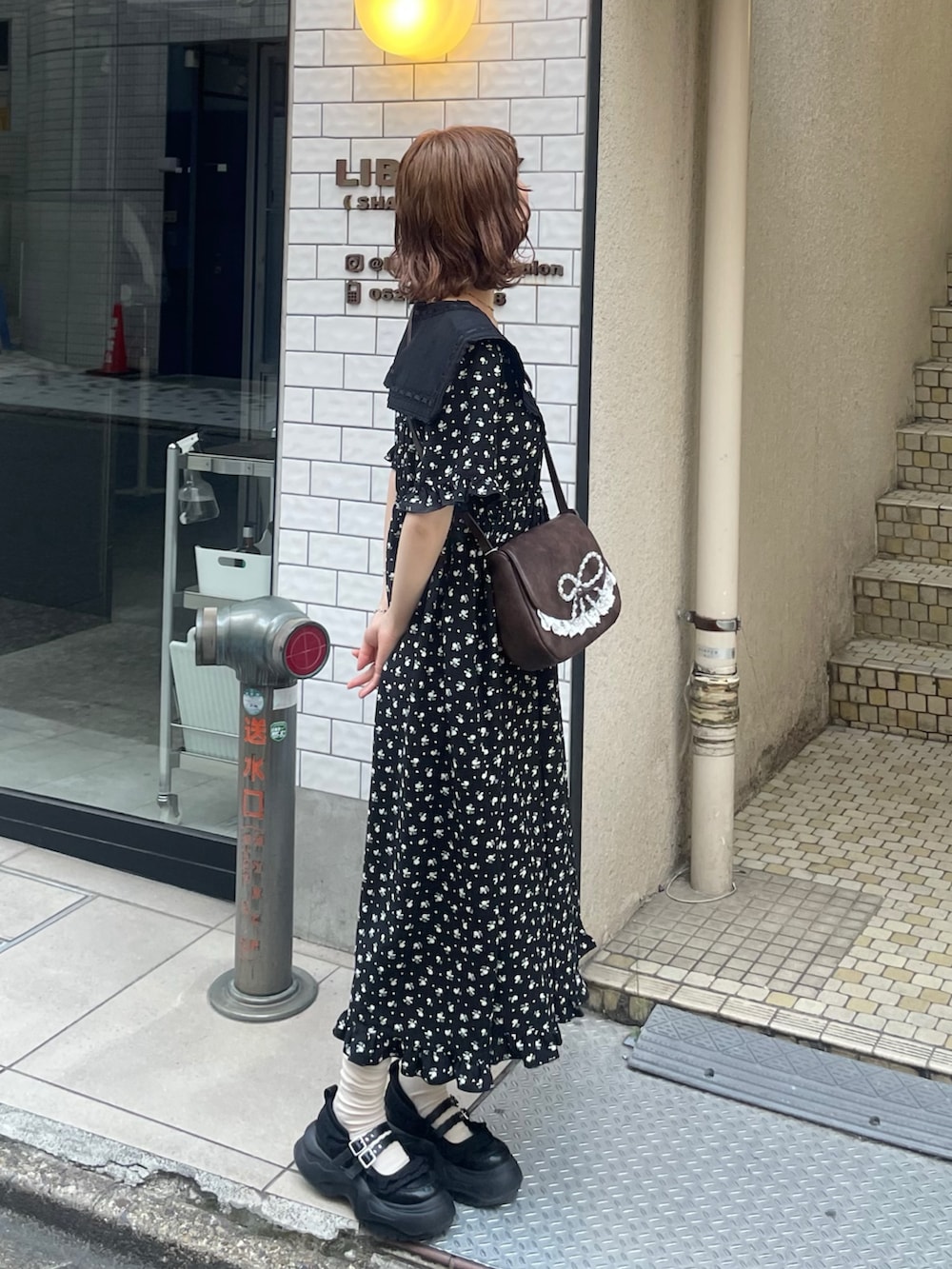 ブラック系のワンピース、ブラック系のスニーカー、ブルー系のショルダーバッグを着用したレディースの春コーディネートの3枚目の写真