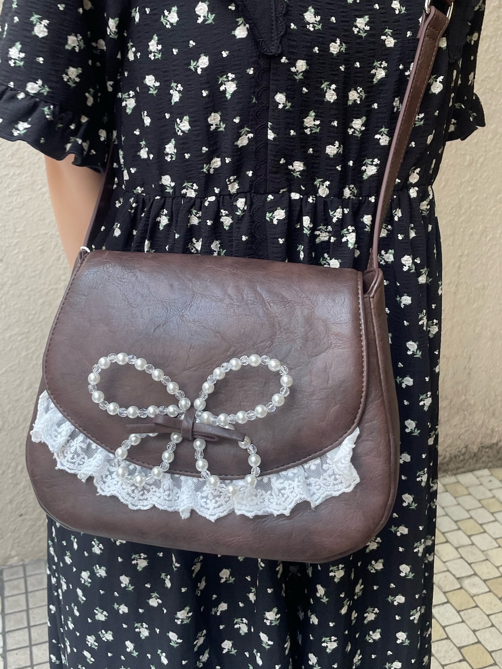ブラック系のワンピース、ブラック系のスニーカー、ブルー系のショルダーバッグを着用したレディースの春コーディネートの6枚目の写真
