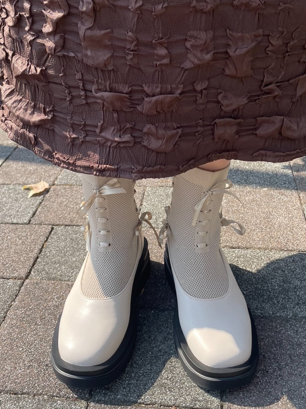 ブラウン系のワンピース、ホワイト系のブルゾン、イエロー系のニット/セーターを着用したレディースの秋コーディネートの9枚目の写真