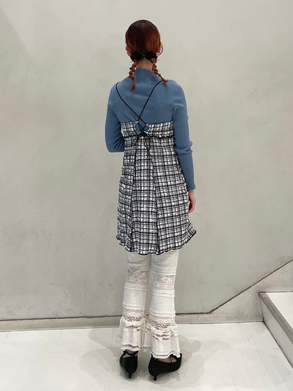 ホワイト系のスラックス、ブルー系のニット/セーター、ブラック系のワンピースを着用したレディースの冬コーディネートの3枚目の写真