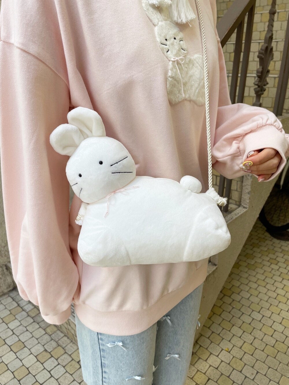 ブルー系のデニムパンツ、ピンク系のスニーカー、ホワイト系のショルダーバッグを着用したレディースの冬コーディネートの5枚目の写真