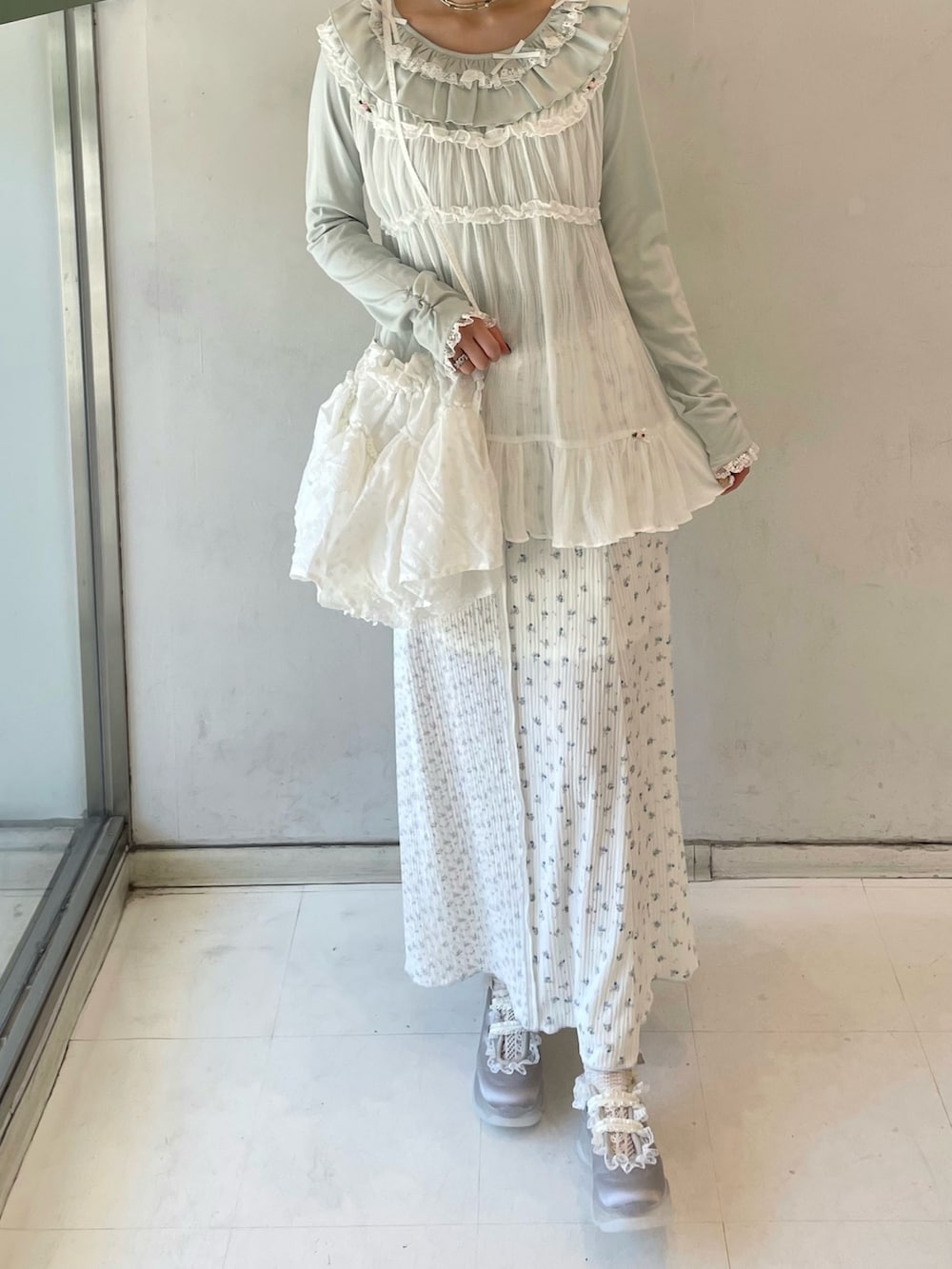 グリーン系のTシャツ/カットソー、ホワイト系のチュニック、ブルー系のスニーカーを着用したレディースの春コーディネートの6枚目の写真