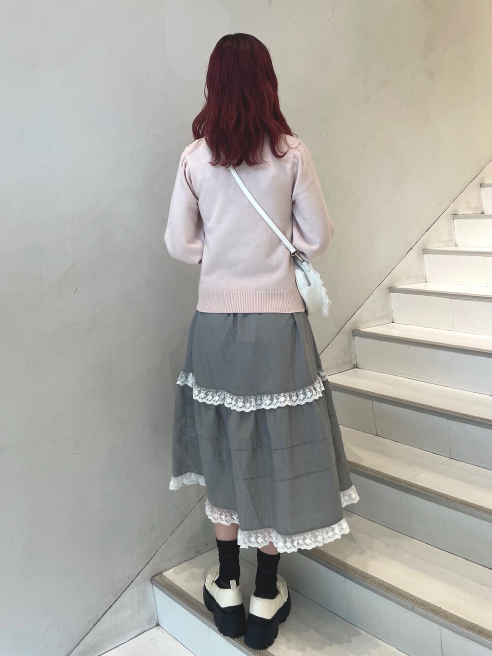 ピンク系のニット/セーター、グレー系のスカート、ホワイト系のショルダーバッグを着用したレディースの秋コーディネートの4枚目の写真