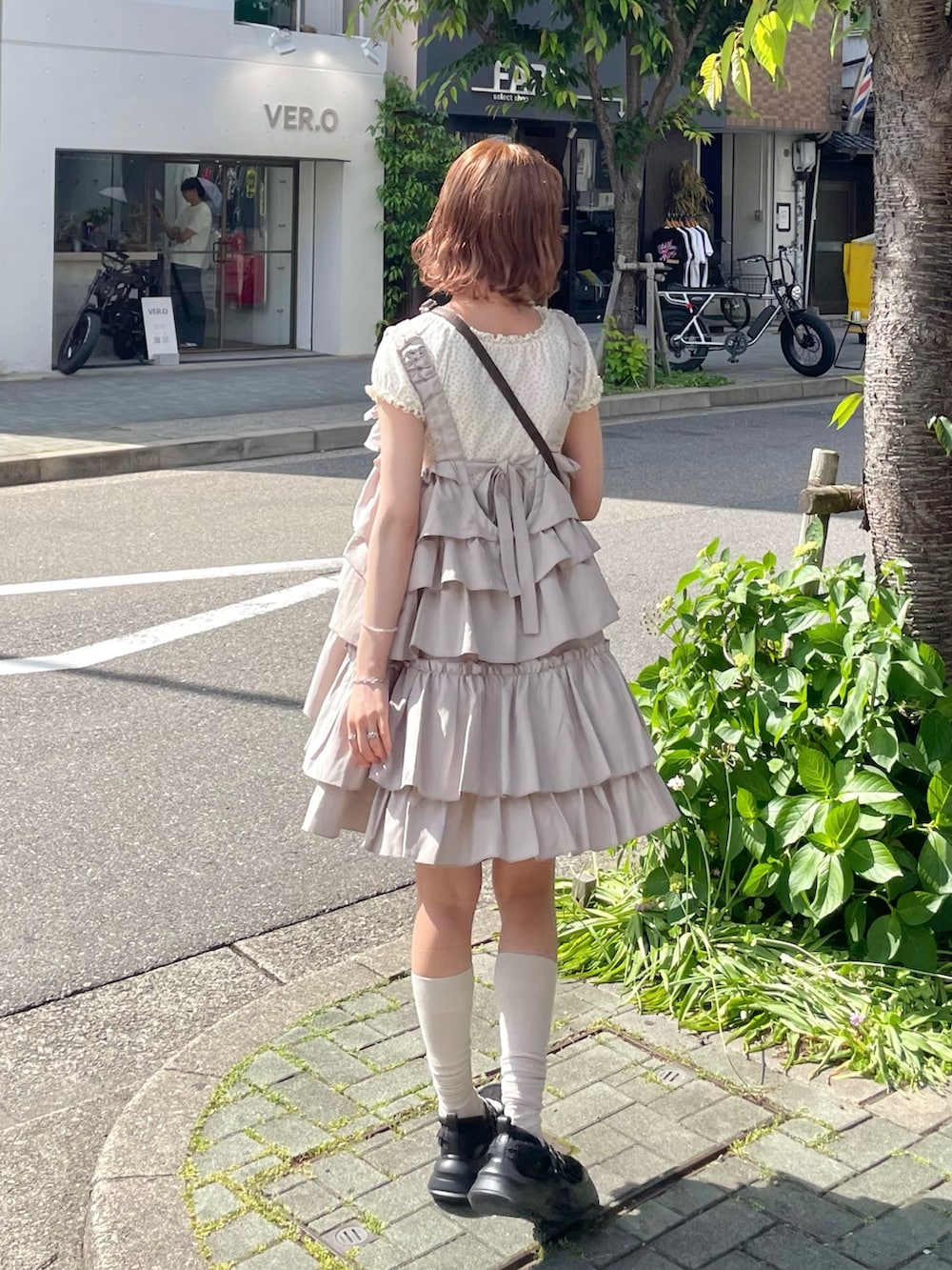 ホワイト系のTシャツ/カットソー、ブラック系のスニーカー、ブラウン系のショルダーバッグを着用したレディースの春コーディネートの4枚目の写真