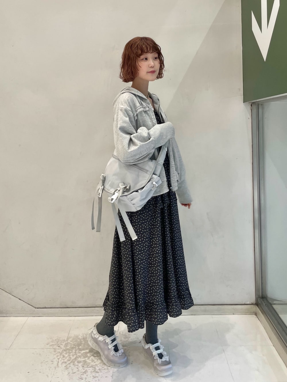 グレー系のパーカー、グレー系のメッセンジャーバッグ、ブラック系のワンピースを着用したレディースの冬コーディネートの2枚目の写真