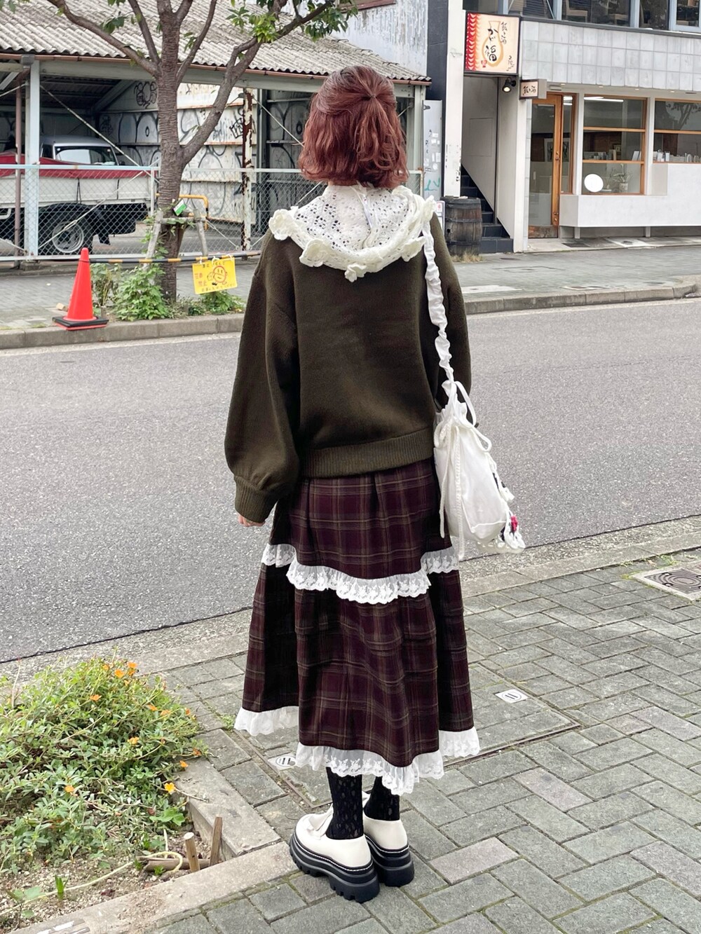 グリーン系のニット/セーター、ホワイト系のショルダーバッグ、ブラウン系のスカートを着用したレディースの秋コーディネートの3枚目の写真