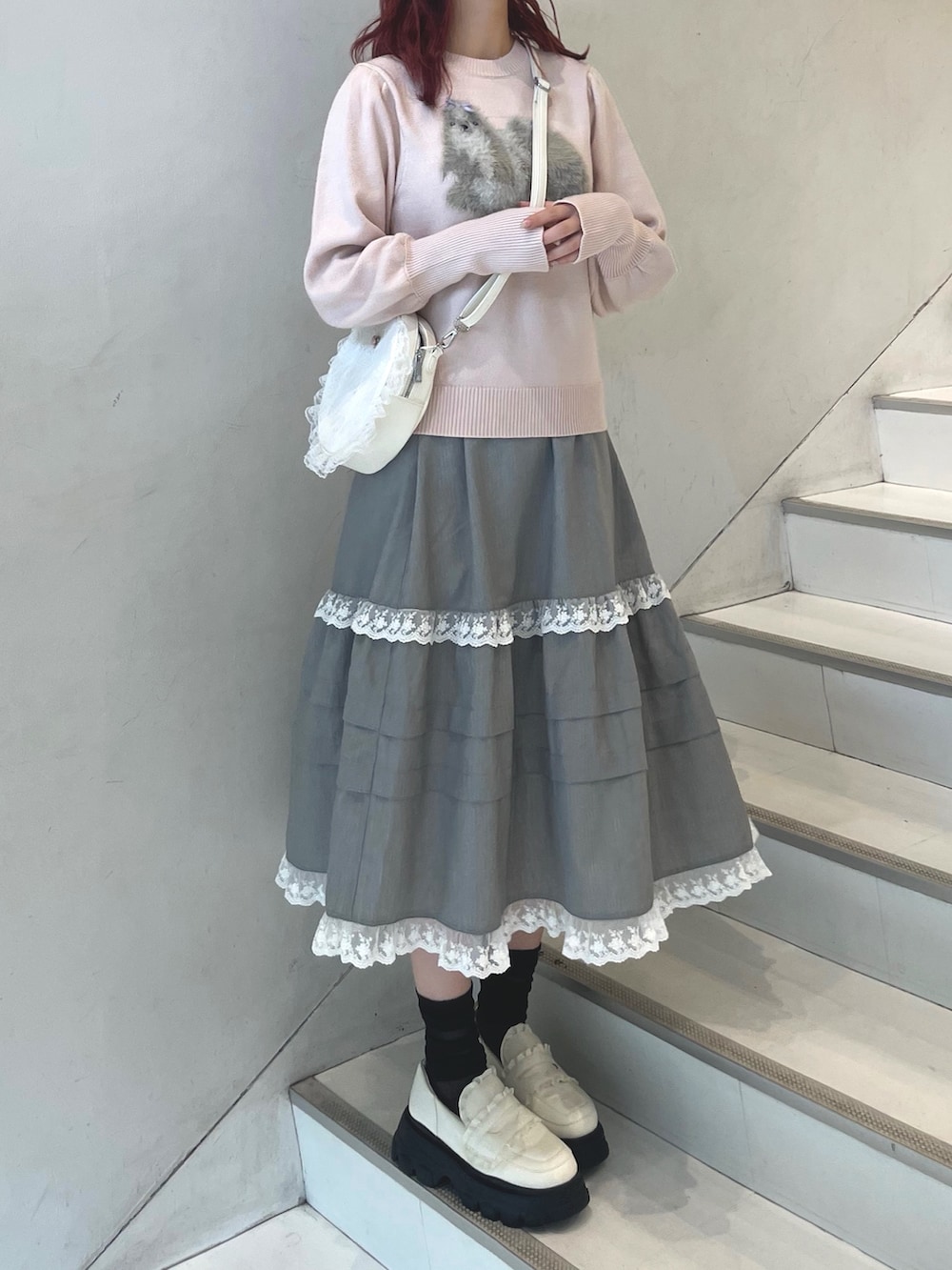 ピンク系のニット/セーター、グレー系のスカート、ホワイト系のショルダーバッグを着用したレディースの秋コーディネートの3枚目の写真