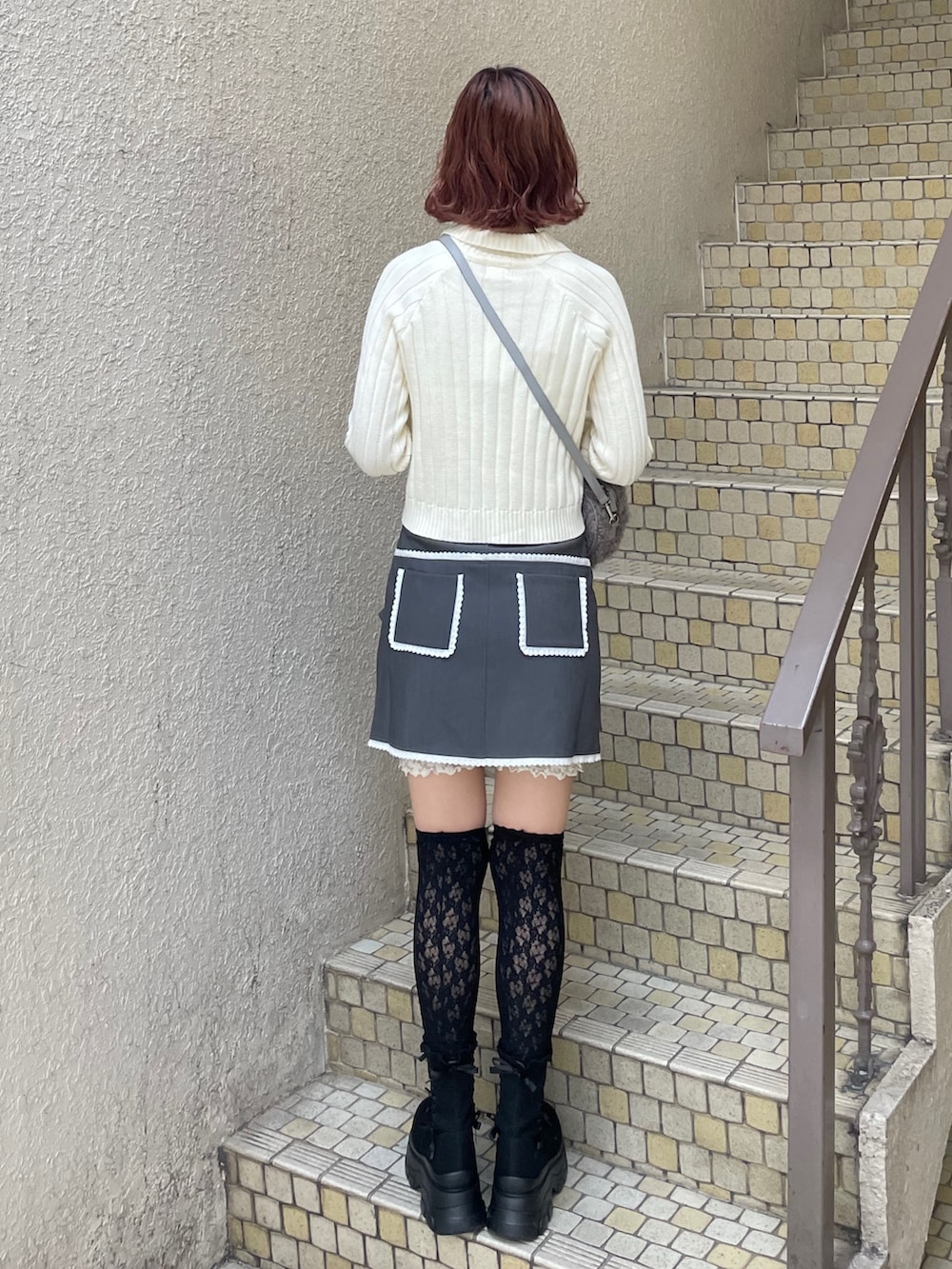 ホワイト系のカーディガン/ボレロ、グレー系のスカート、グレー系のショルダーバッグを着用したレディースの秋コーディネートの2枚目の写真