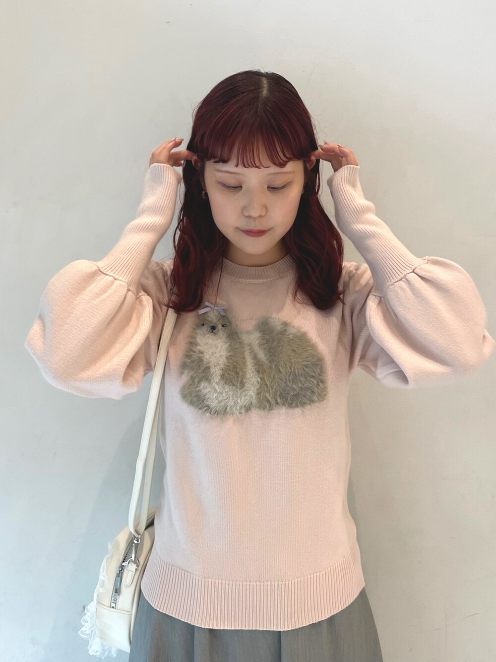 ピンク系のニット/セーター、グレー系のスカート、ホワイト系のショルダーバッグを着用したレディースの秋コーディネートの5枚目の写真