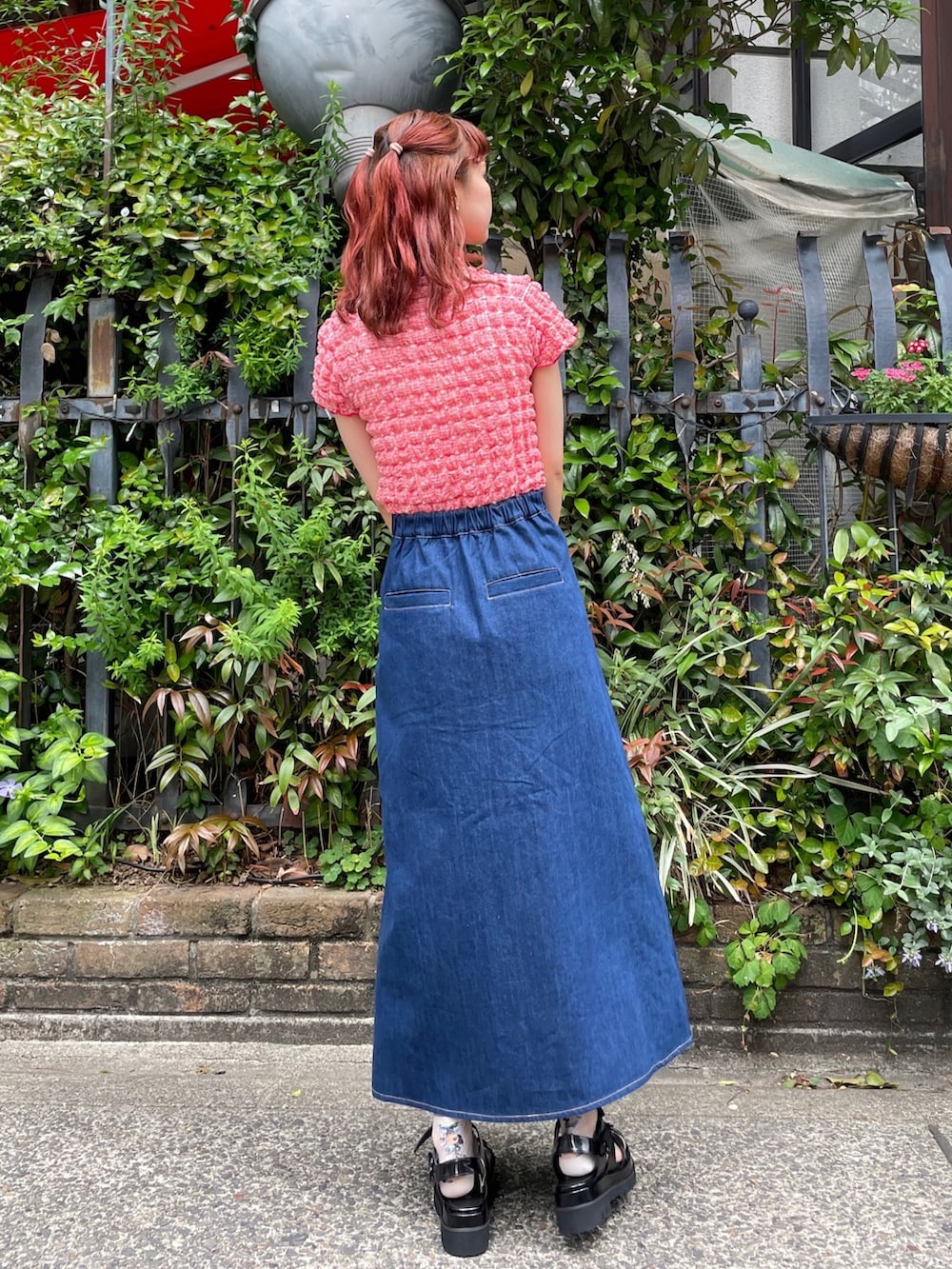 ブルー系のデニムスカート、レッド系のTシャツ/カットソー、ブラック系のサンダルを着用したレディースの春コーディネートの3枚目の写真