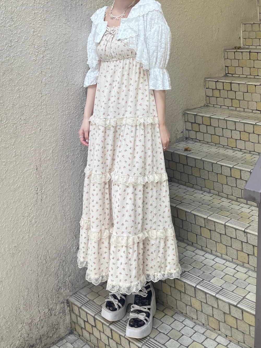 ベージュ系のワンピース、ホワイト系のカーディガン/ボレロ、ピンク系のショルダーバッグを着用したレディースの春コーディネートの3枚目の写真