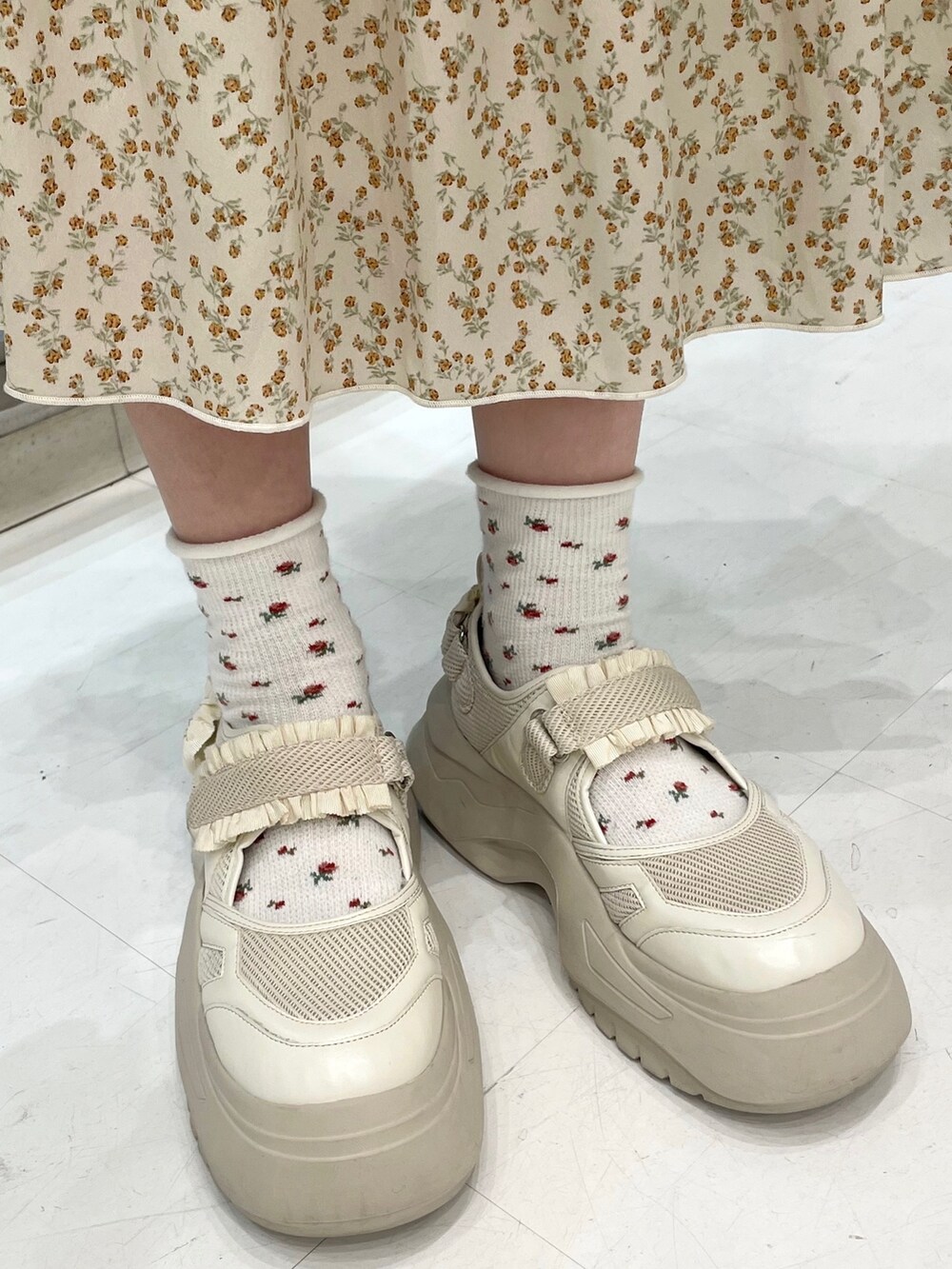 ホワイト系のスカート、ホワイト系のスニーカー、ブルー系のカーディガン/ボレロを着用したレディースの秋コーディネートの5枚目の写真