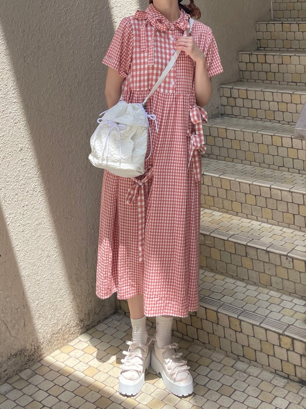レッド系のワンピース、ホワイト系のショルダーバッグ、ホワイト系のサンダルを着用したレディースの春コーディネートの4枚目の写真