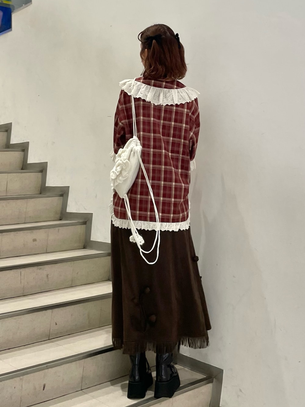 レッド系のシャツ/ブラウス、ブラウン系のスカート、ホワイト系のバックパック/リュックを着用したレディースの秋コーディネートの2枚目の写真