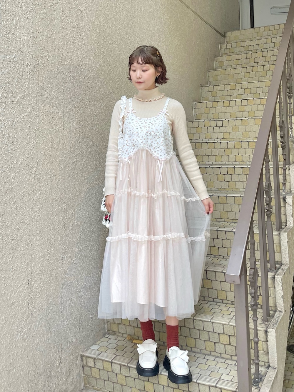 ホワイト系のニット/セーター、ピンク系のワンピース、ホワイト系のショルダーバッグを着用したレディースの冬コーディネートの4枚目の写真