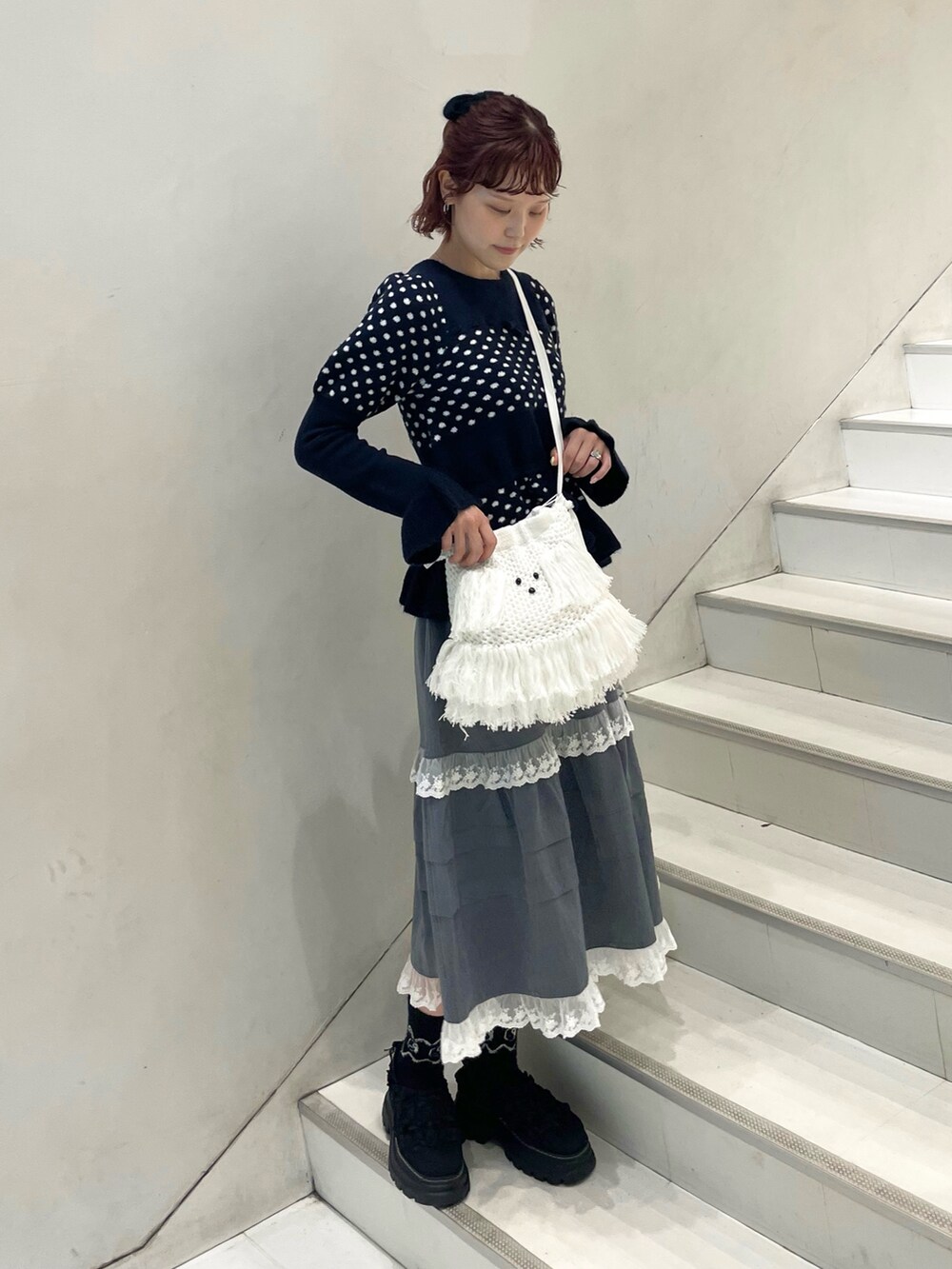 ブルー系のニット/セーター、グレー系のスカート、ホワイト系のショルダーバッグを着用したレディースの秋コーディネートの3枚目の写真