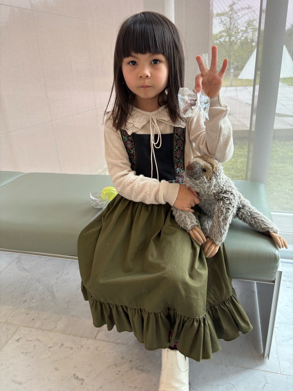 ベージュ系のニット/セーター、グリーン系のワンピース、ホワイト系のブーツを着用したキッズの春コーディネートの2枚目の写真