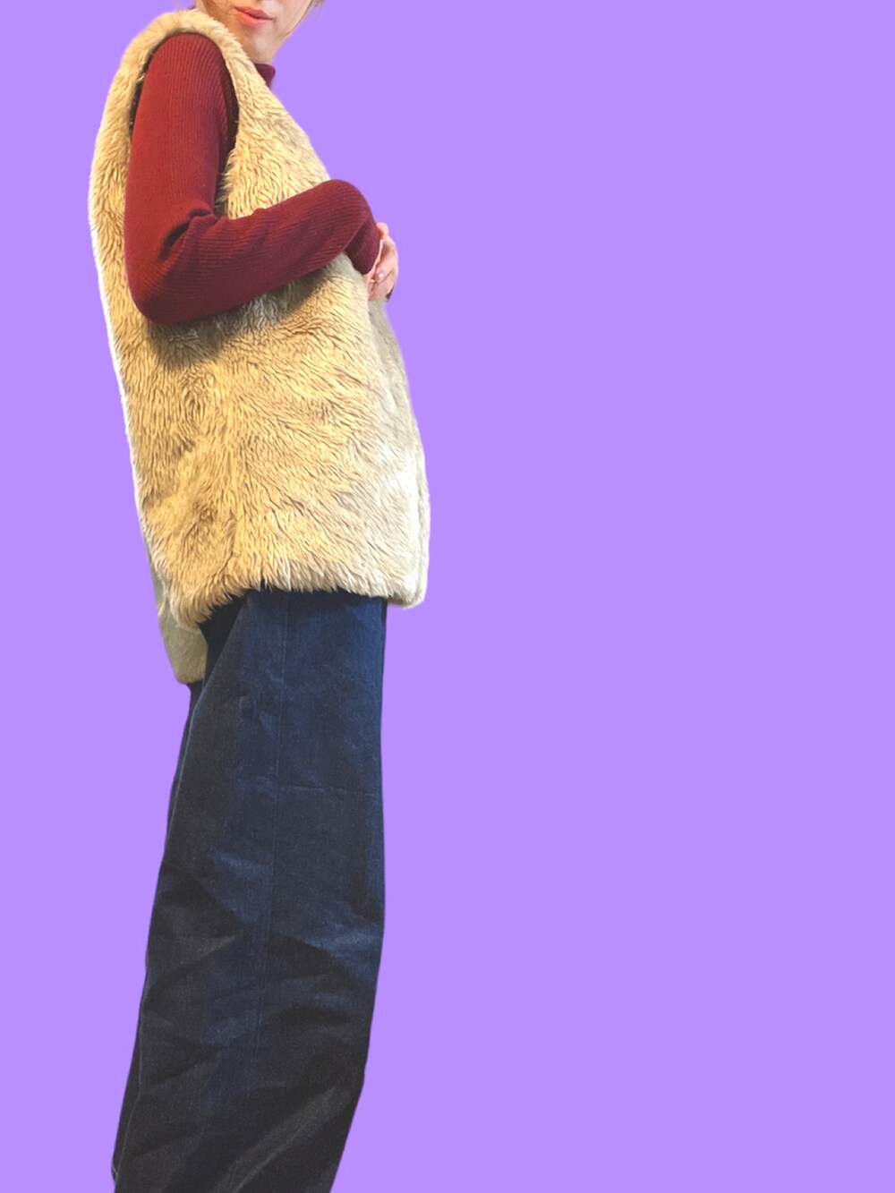 レッド系のニット/セーター、ベージュ系のベスト、ブルー系のデニムパンツを着用したレディースの冬コーディネートの2枚目の写真