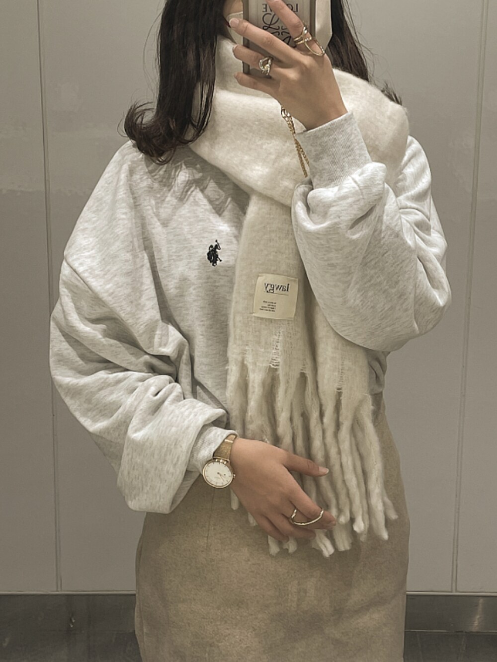 グレー系のスウェット、ホワイト系のマフラー、ピンク系のアナログ腕時計を着用したレディースの冬コーディネートの3枚目の写真