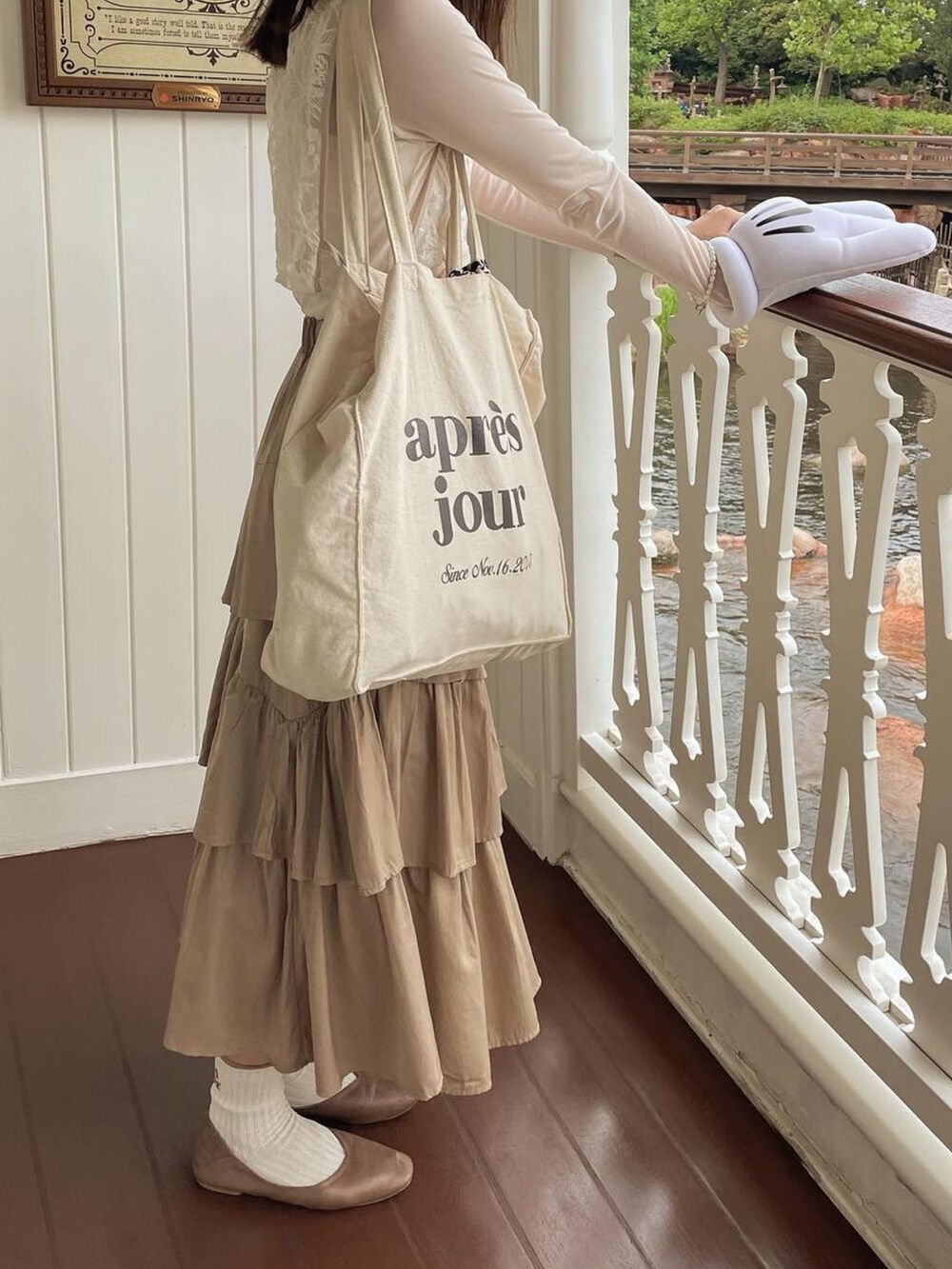 ホワイト系のベスト、ホワイト系のトートバッグ、ベージュ系のスカートを着用したレディースの秋コーディネートの5枚目の写真