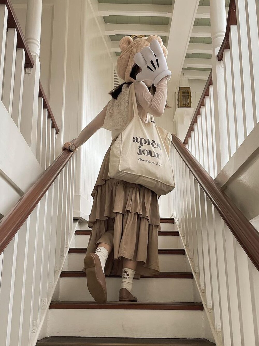 ホワイト系のベスト、ホワイト系のトートバッグ、ベージュ系のスカートを着用したレディースの秋コーディネートの2枚目の写真