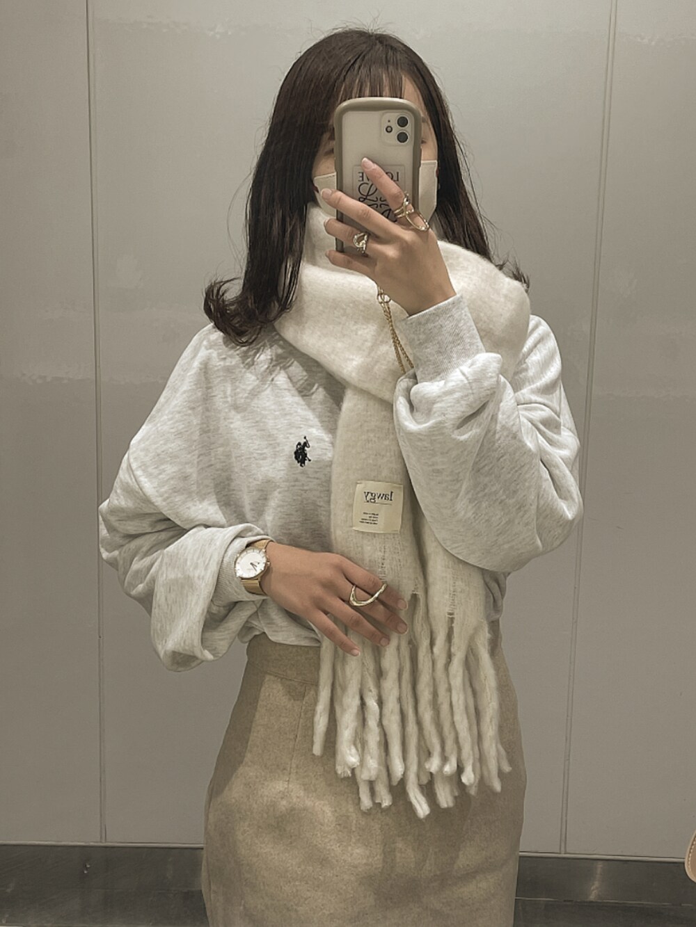 グレー系のスウェット、ホワイト系のマフラー、ピンク系のアナログ腕時計を着用したレディースの冬コーディネートの2枚目の写真