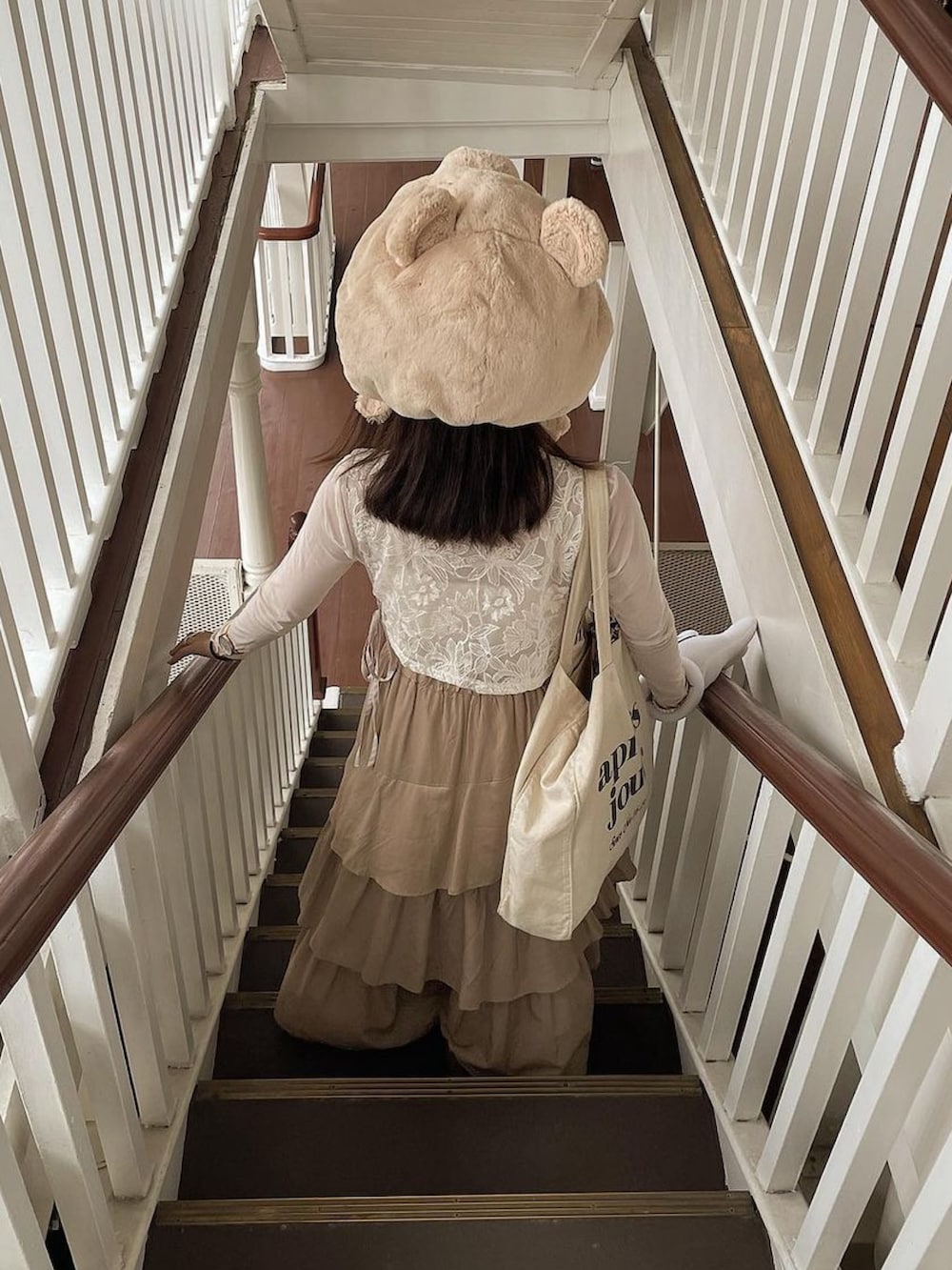 ホワイト系のベスト、ホワイト系のトートバッグ、ベージュ系のスカートを着用したレディースの秋コーディネートの3枚目の写真