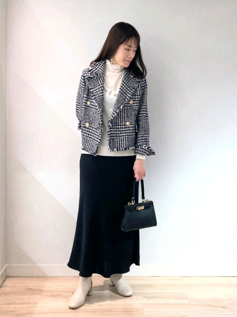 ブラック系のショルダーバッグ、ホワイト系のブーツ、ブラック系のスカートを着用したレディースの冬コーディネートの2枚目の写真