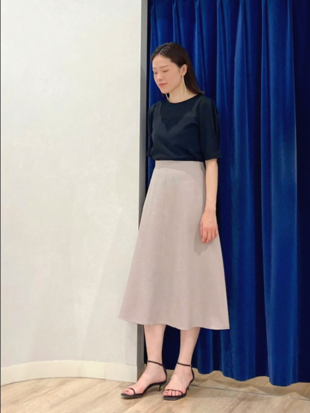 ベージュ系のスカート、ブラック系のTシャツ/カットソー、ゴールド系のピアス（両耳用）を着用したレディースの夏コーディネートの3枚目の写真