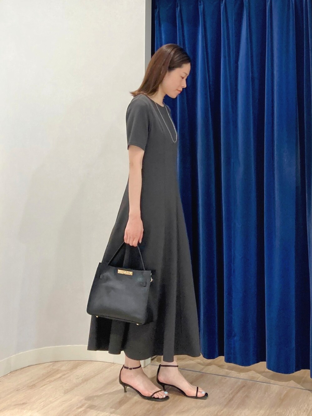 ベージュ系のテーラードジャケット、ブラック系のショルダーバッグ、グレー系のワンピースを着用したレディースの夏コーディネートの7枚目の写真